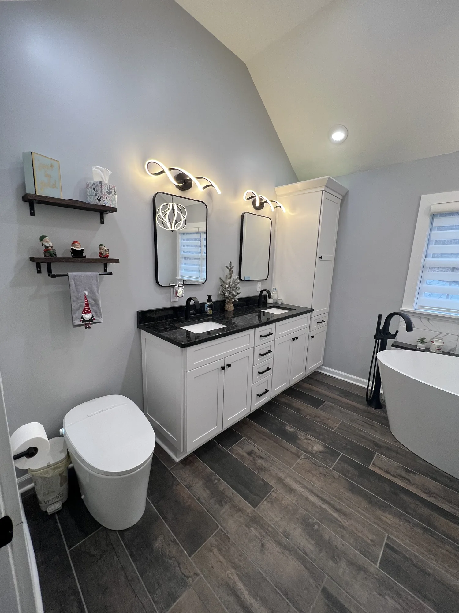Remodeled bathroom with a white double vanity, freestanding tub, and plank tile floor near Pittsburgh