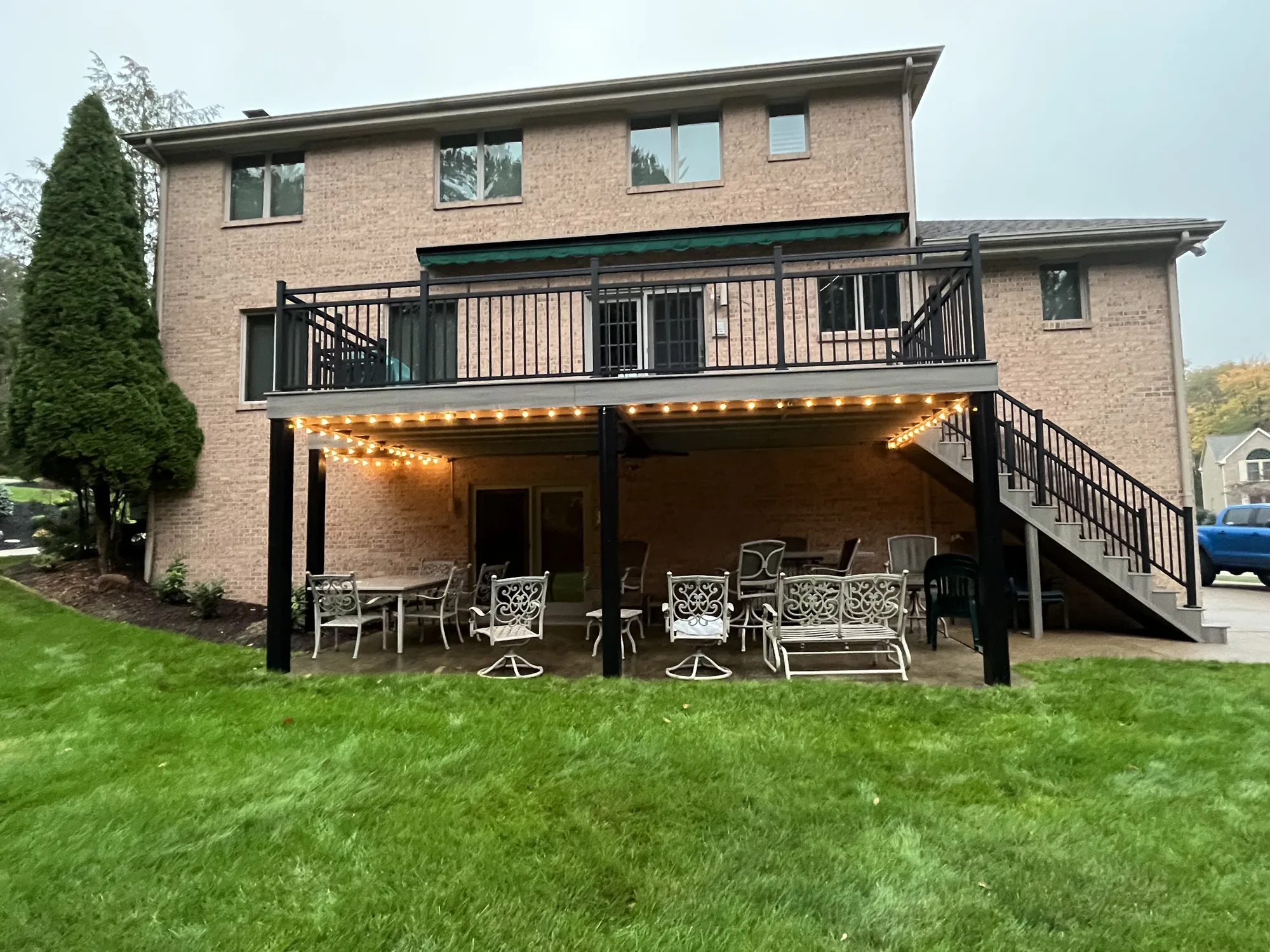 Raised composite deck with under deck patio and string lights on a brick home near Allison Park