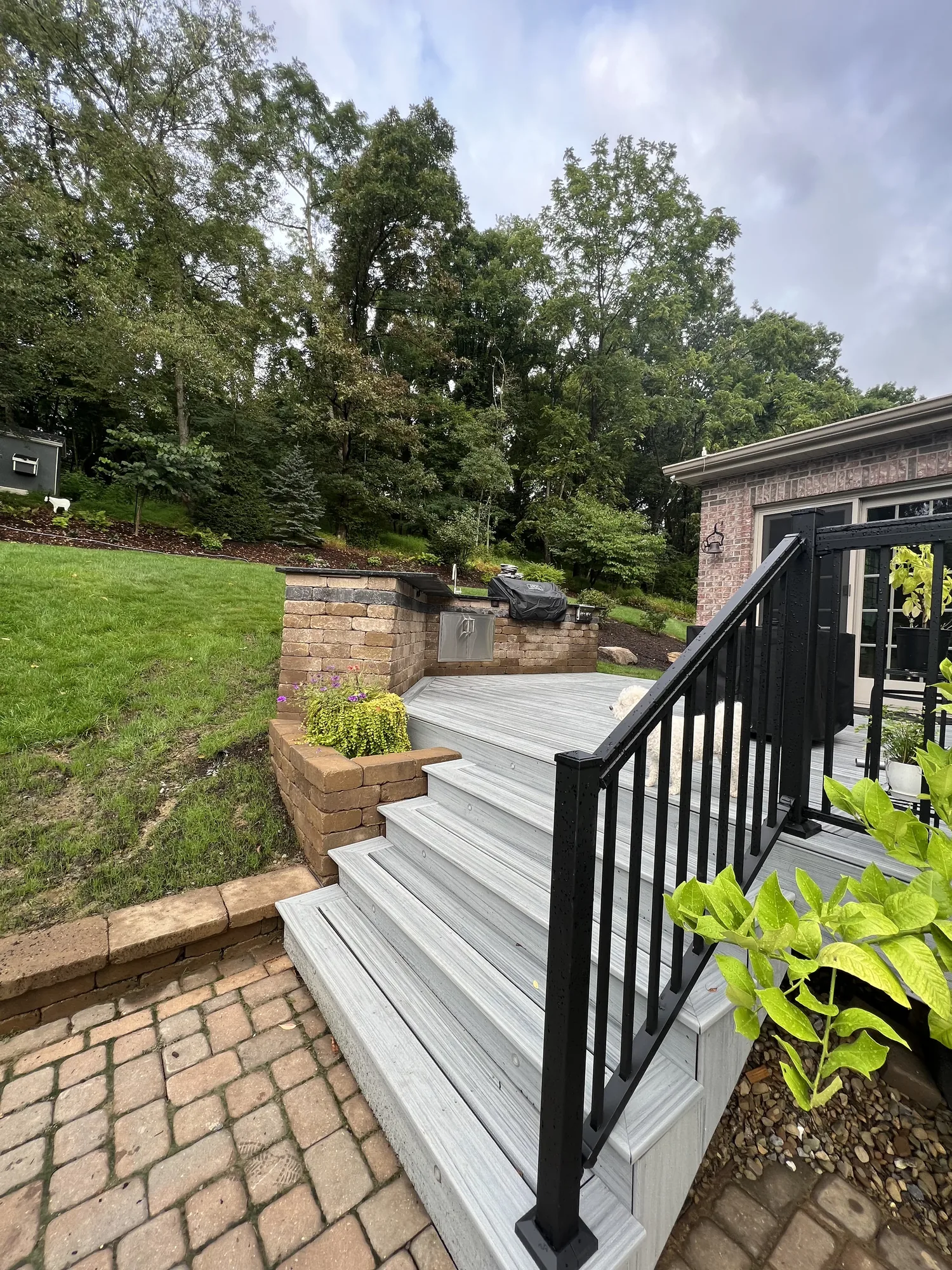 Deck stairs to a paver patio with a block retaining wall planter at a North Hills Pittsburgh home