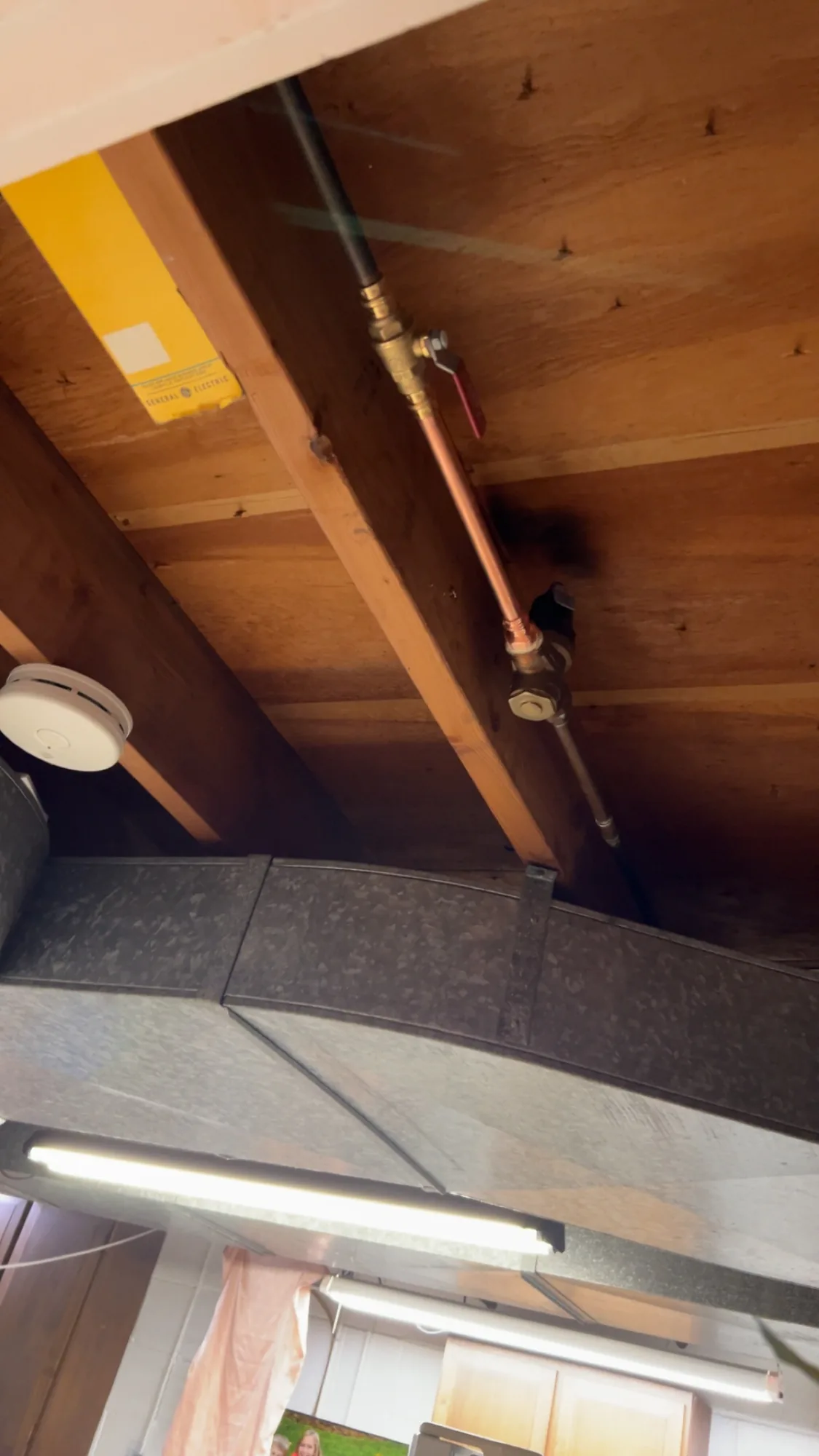 Black iron gas line with brass shutoff valve running through ceiling joists in a Pittsburgh area garage