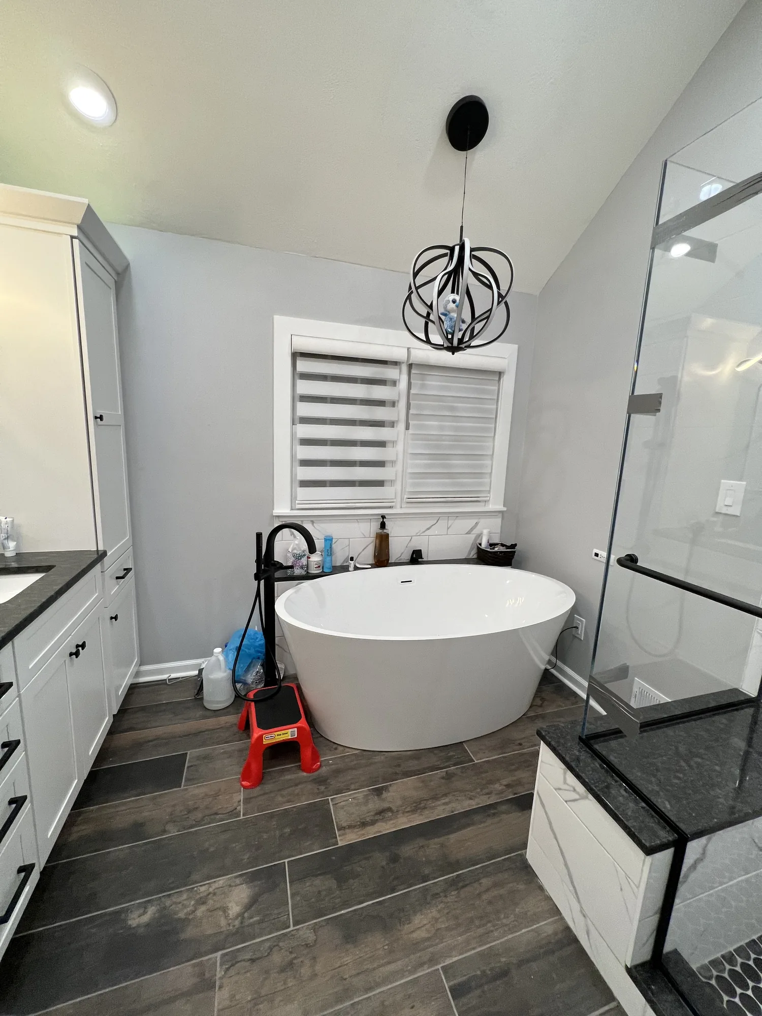 Freestanding soaking tub and wood look tile wall in a finished bathroom remodel near Pittsburgh