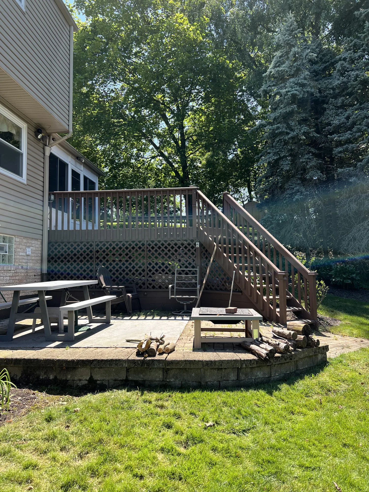Composite deck with stairs to a patio and a block retaining wall at a Pittsburgh area home