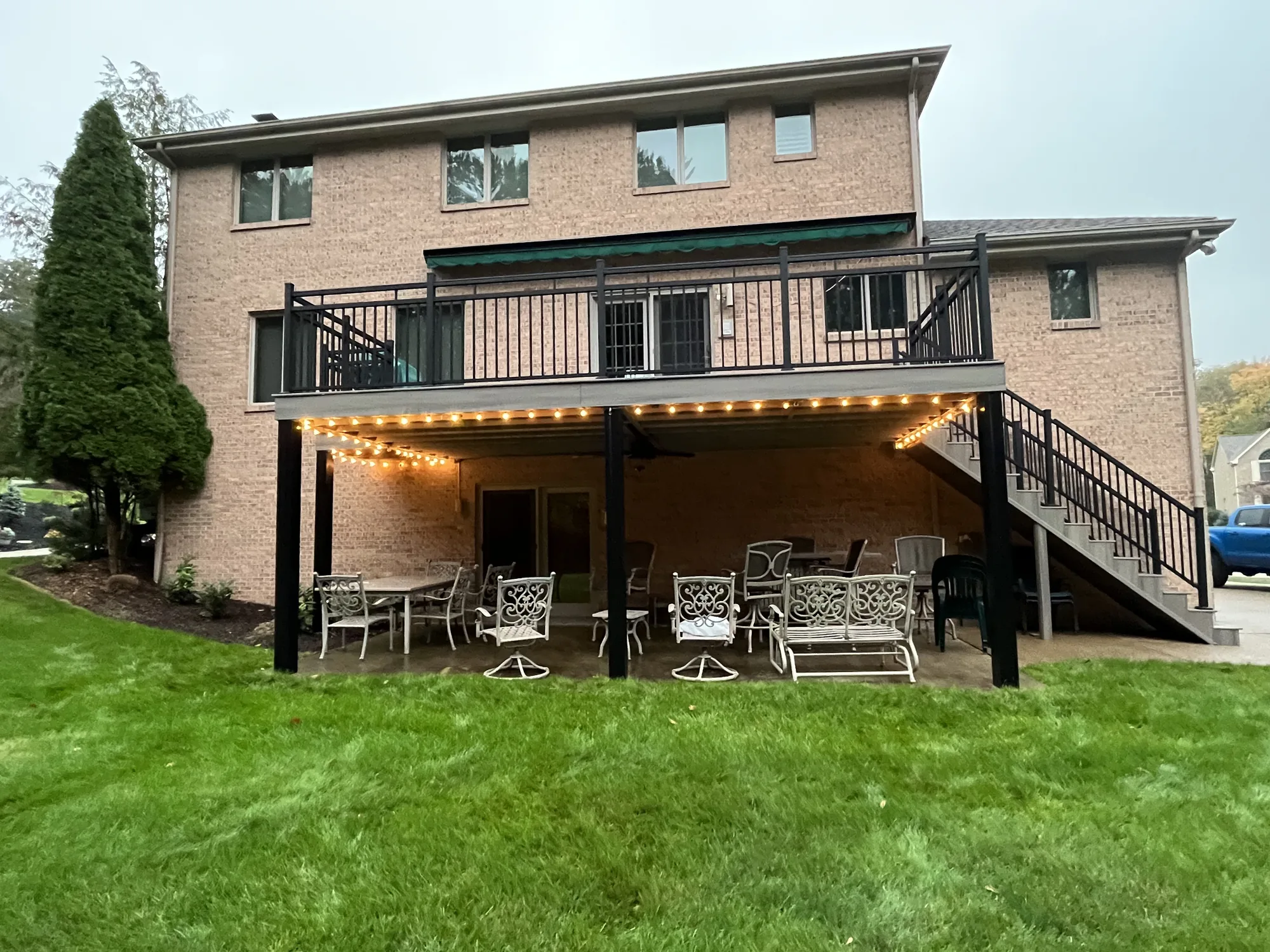 Elevated deck with black aluminum railing over a lit patio at a brick home in the North Hills of Pittsburgh