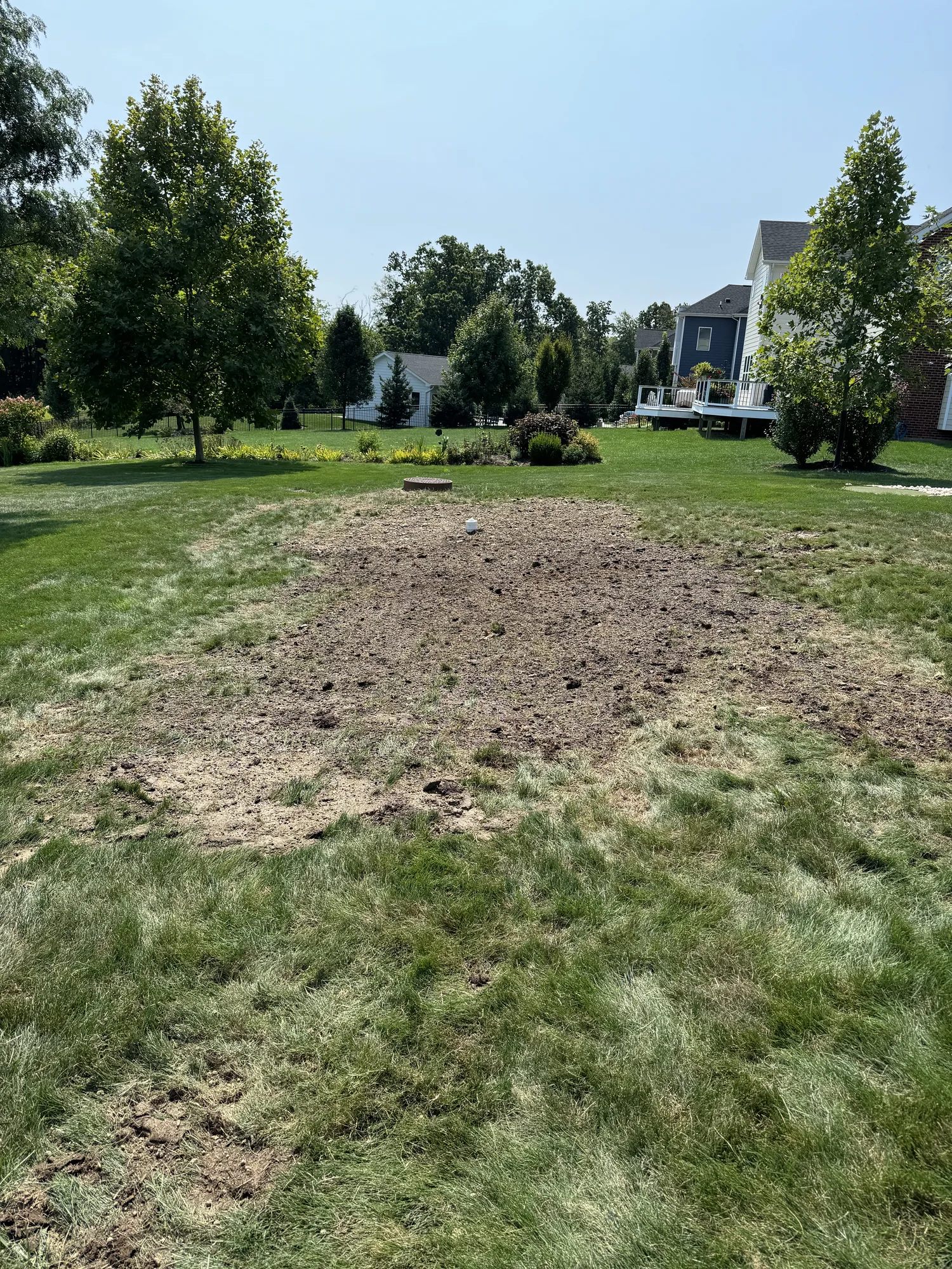 Backfilled and graded trench line across a residential back yard after underground utility work