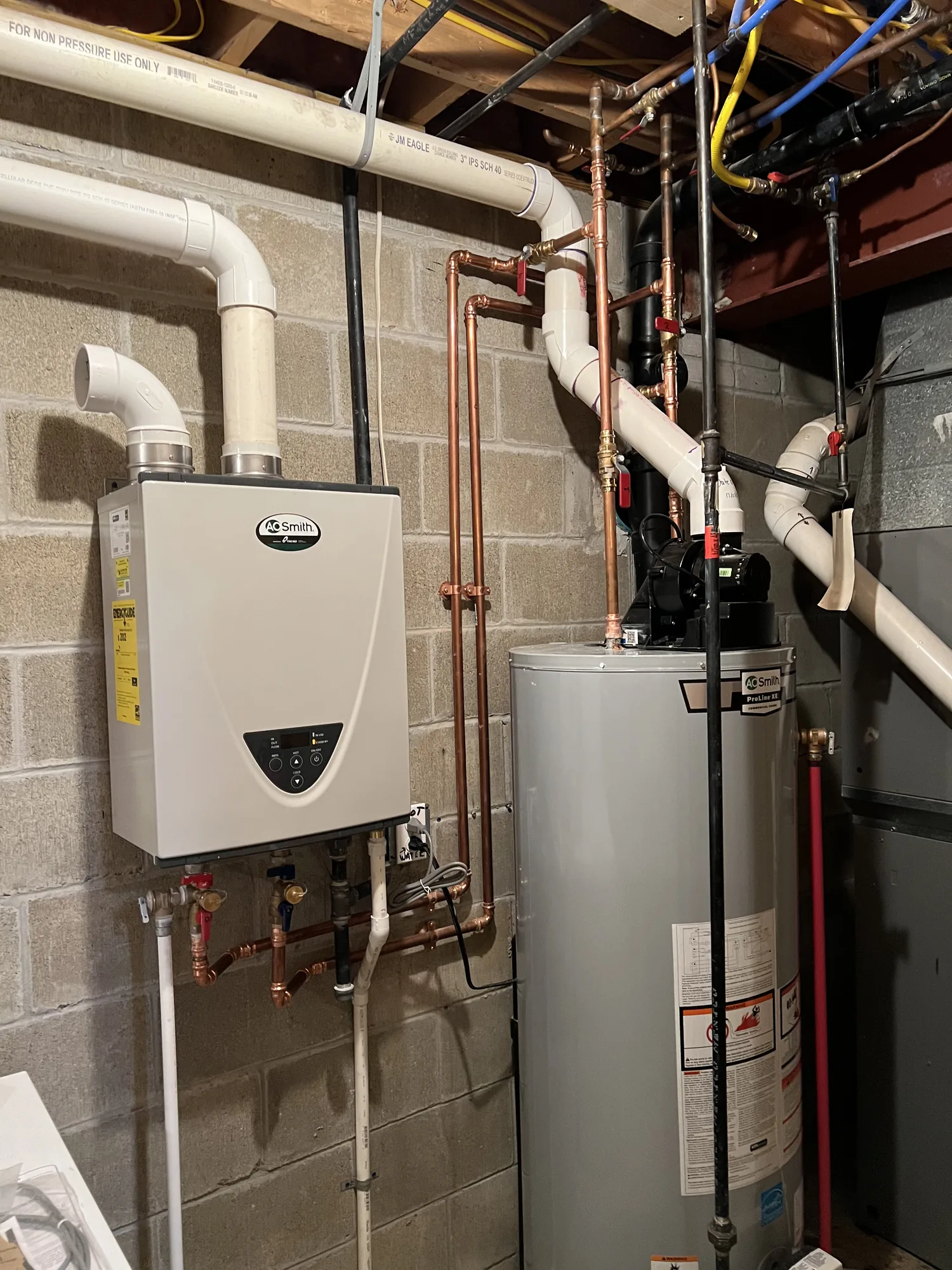 Basement mechanical room with tankless unit, gas water heater and copper piping after a utility upgrade