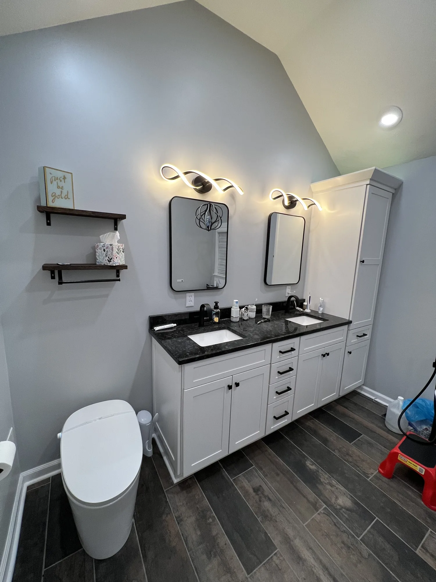 Finished bathroom with white double vanity, stone countertop and wood look tile floor by a Pittsburgh area contractor