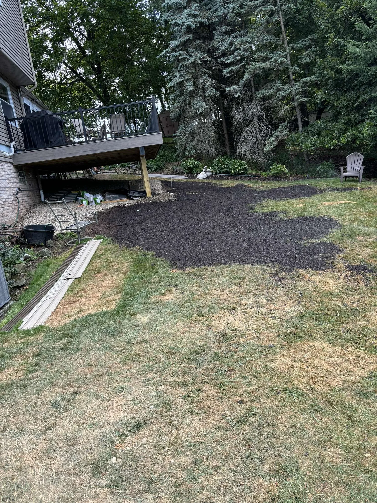 Fresh topsoil graded and leveled in a back yard under a raised deck after excavation work
