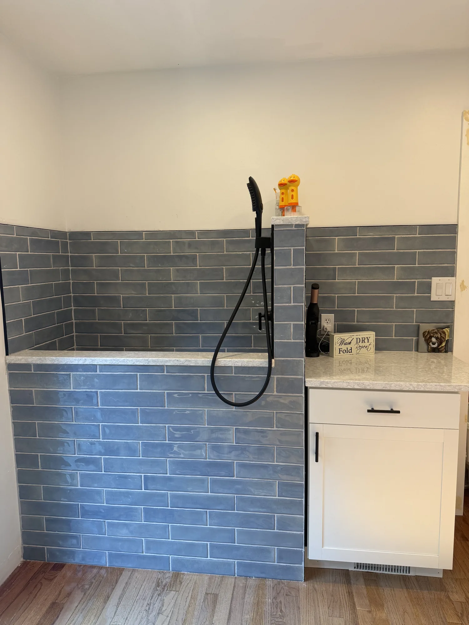 Laundry room with blue vertical subway tile and a white cabinet after an interior remodel