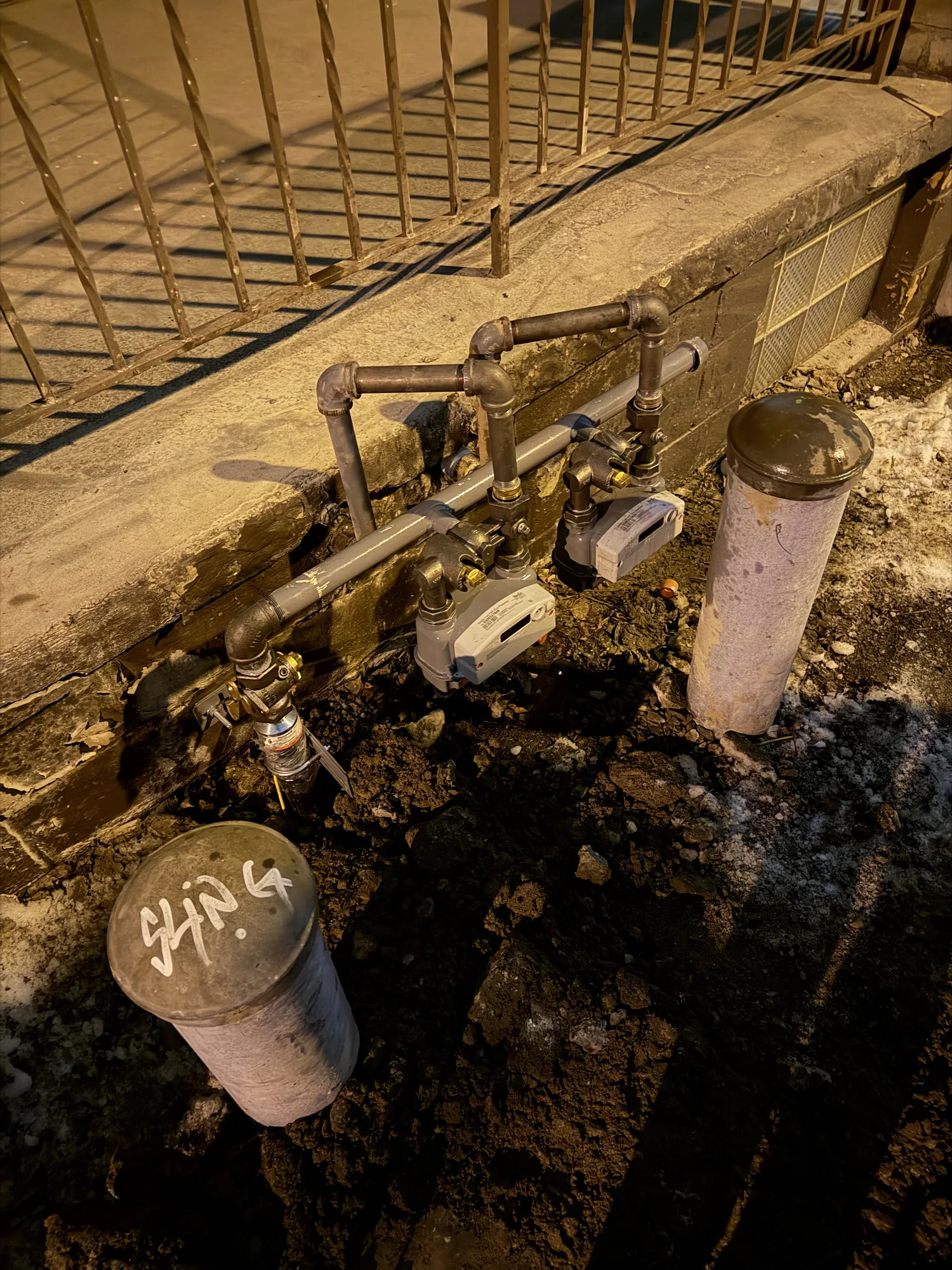 Gas meters and service piping at a house foundation with the concrete and soil opened for a gas line replacement