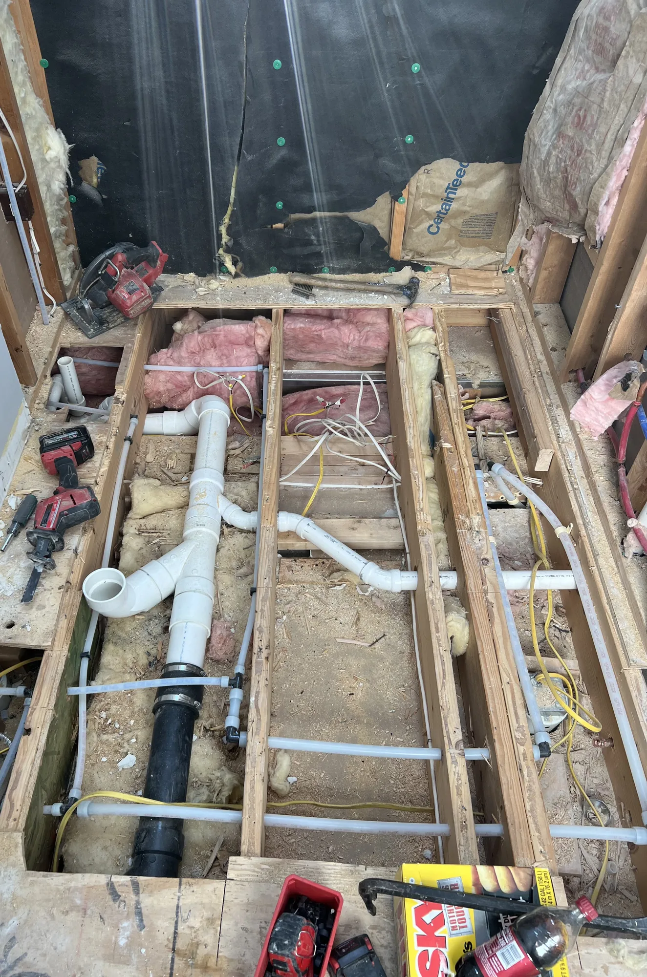 Bathroom floor opened to the joists with new PVC drain lines and PEX supply piping during a remodel