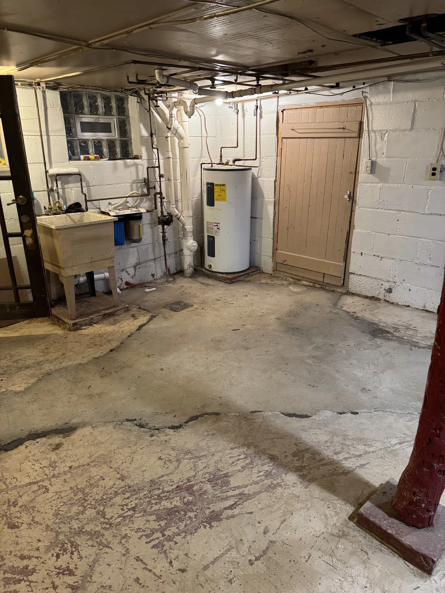 Unfinished basement with a cracked concrete foundation wall before renovation work