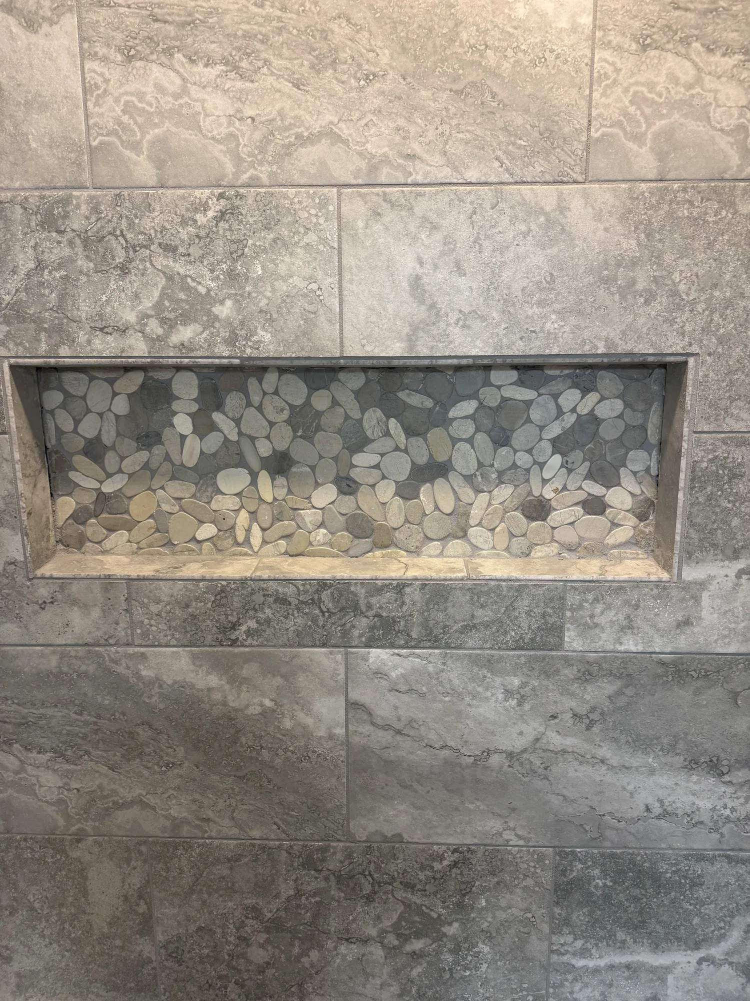 Tiled shower niche with river rock accent in a Pittsburgh area bathroom remodel