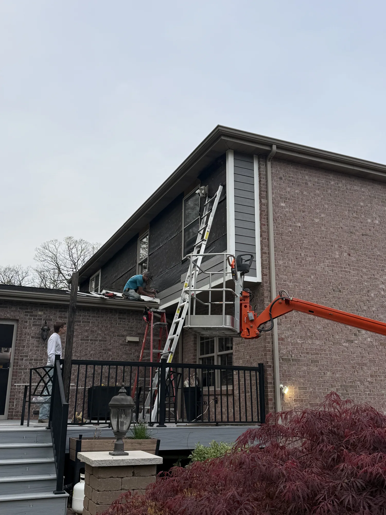 Crew working from a boom lift on the roofline of a brick home near Allison Park