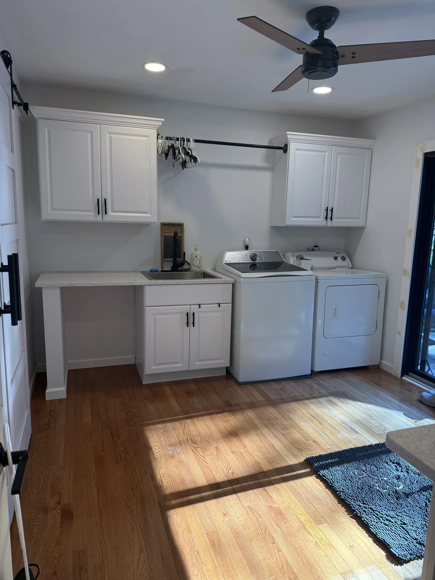 Finished laundry room with white cabinets and stacked washer and dryer in a remodeled home