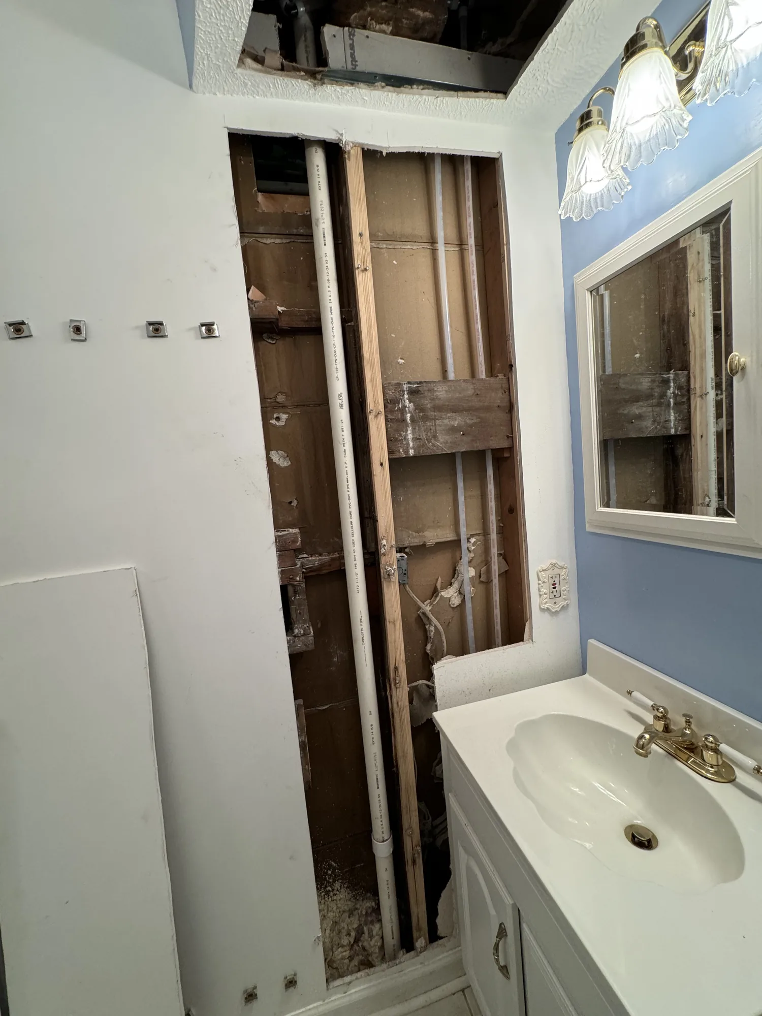 Dated bathroom with wall opened for new supply lines before a full remodel