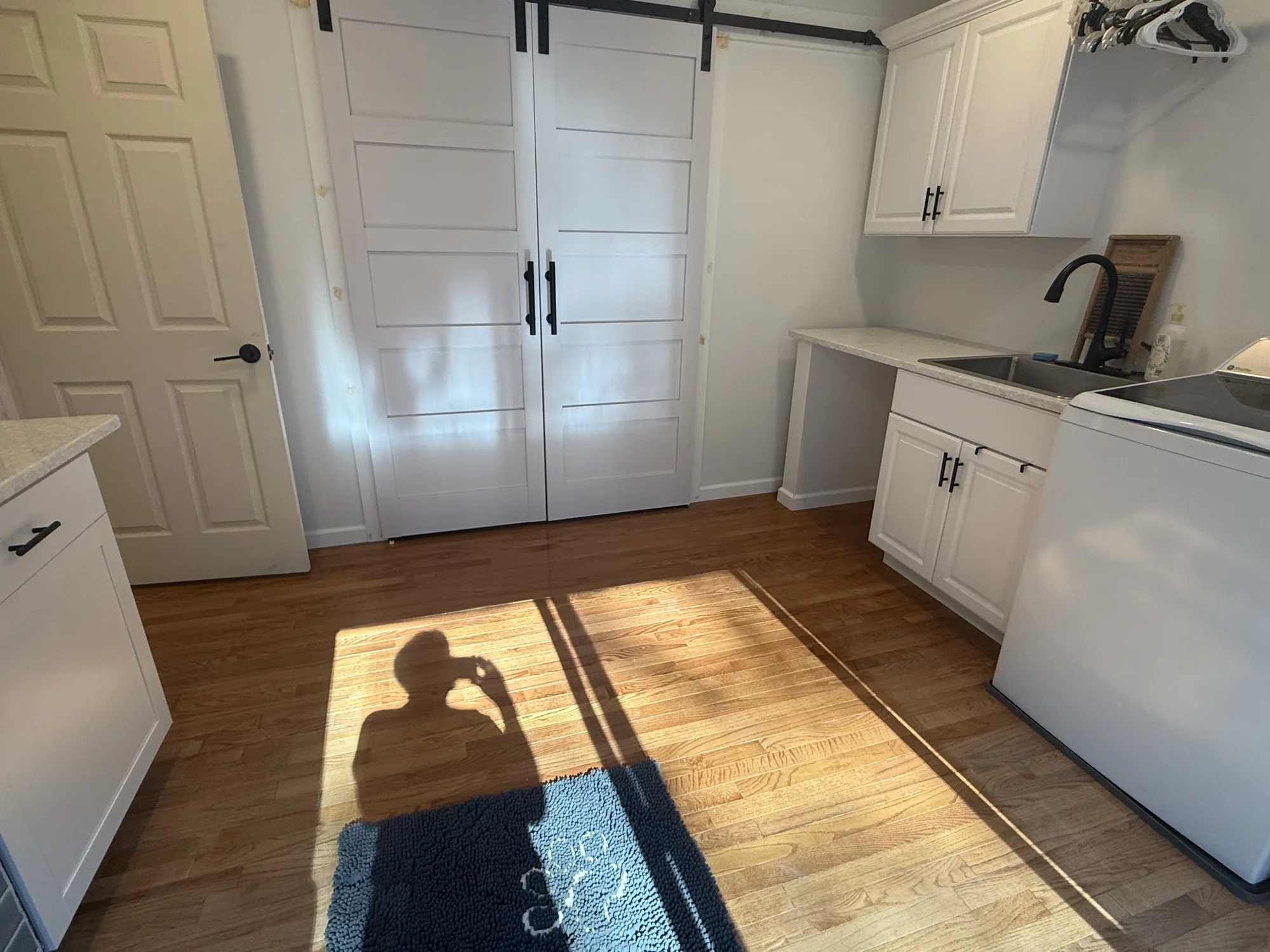 Remodeled laundry room with barn doors, white cabinets, and matte black faucet in a Pittsburgh home