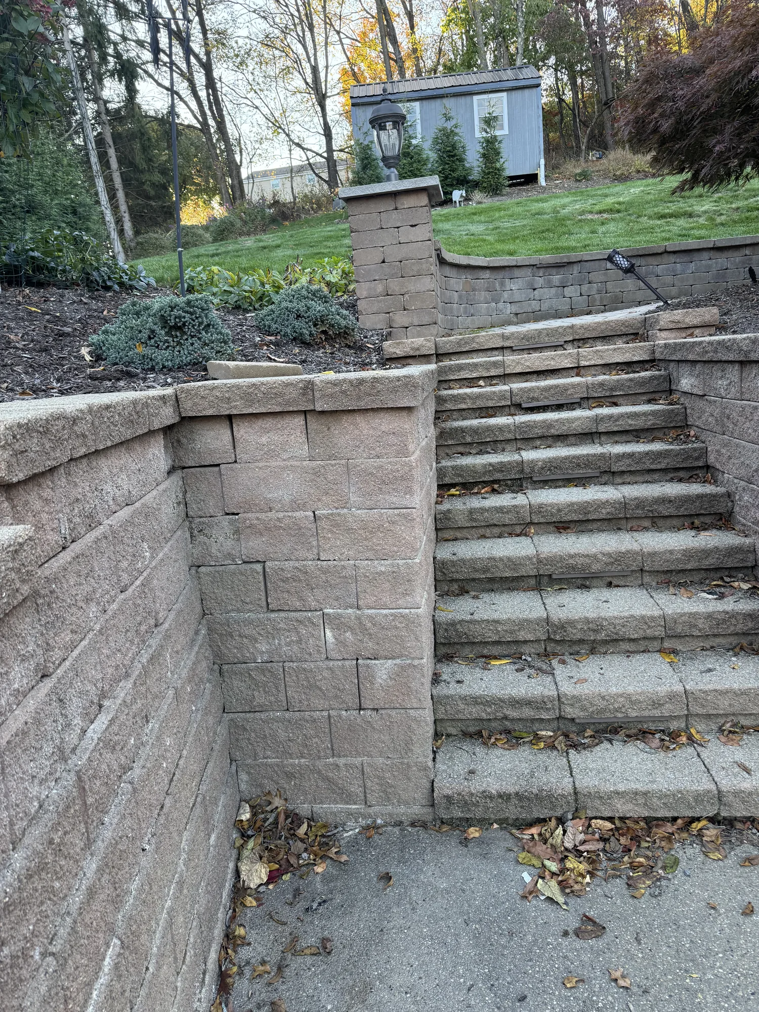 Block retaining wall and steps leading to a paver walkway on a sloped North Hills property