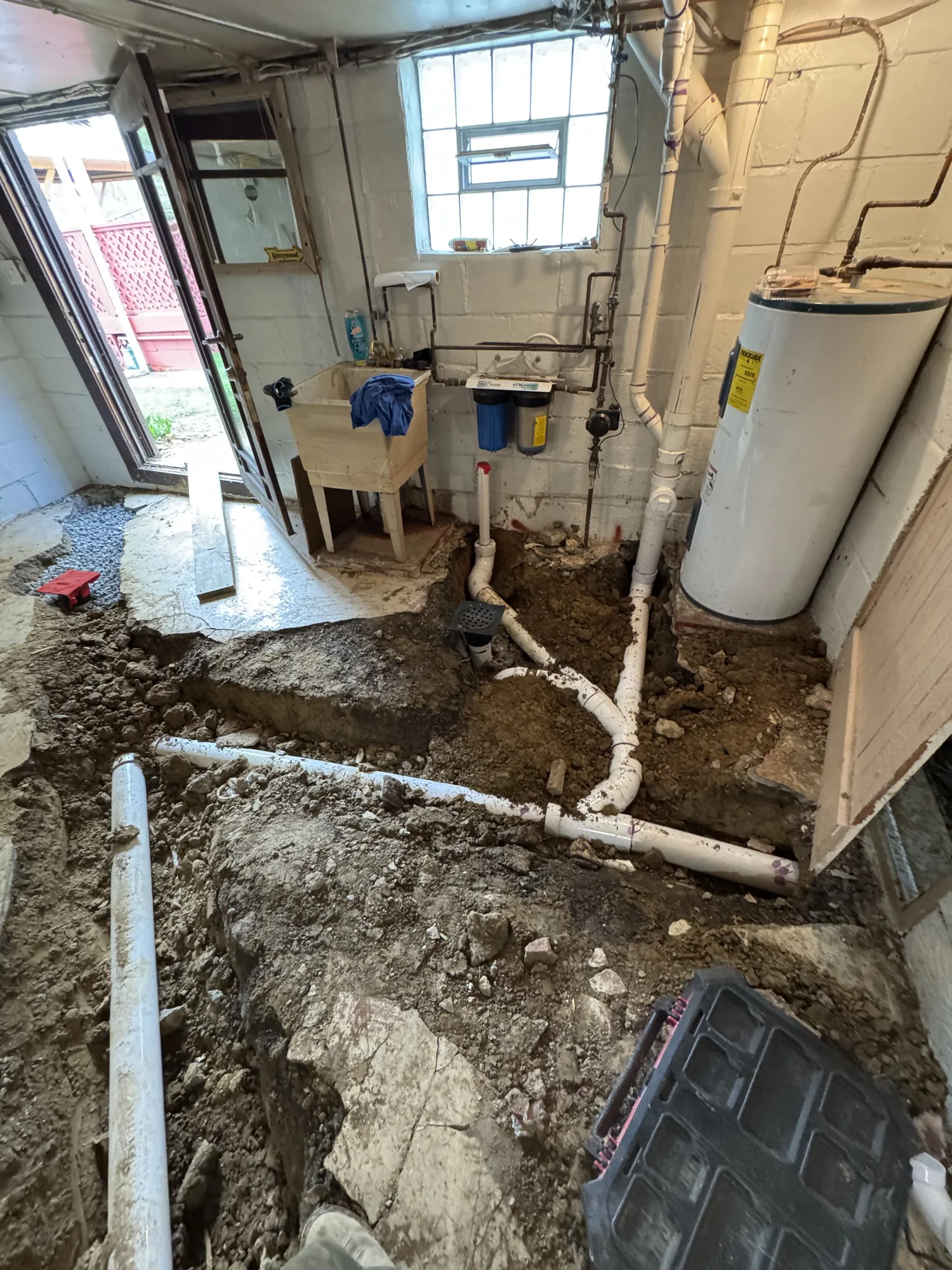 New PVC drain line set in an open basement trench during a sewer line replacement in Pittsburgh