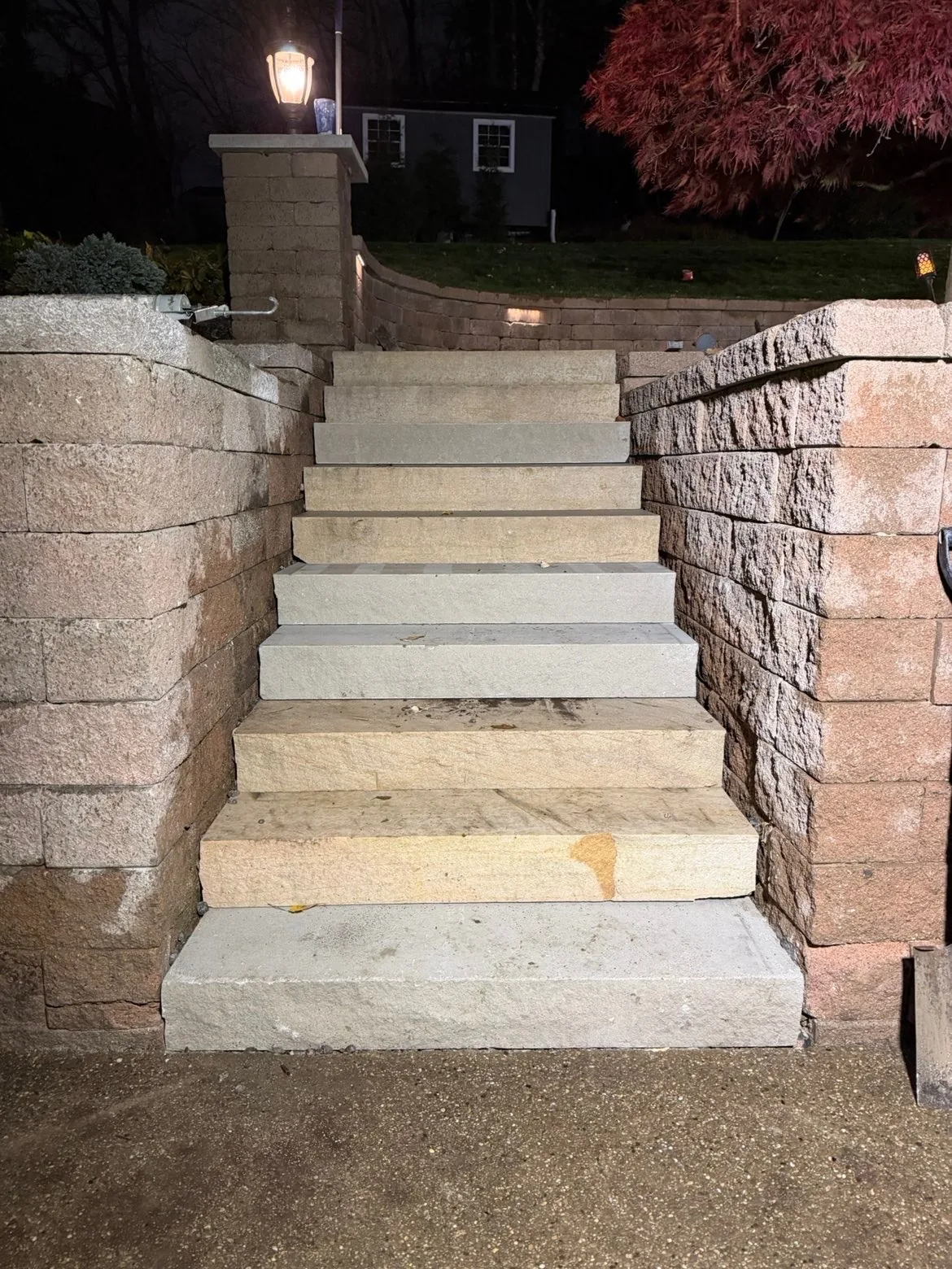 Block retaining walls and stone steps lit at night on a hillside property in the North Hills