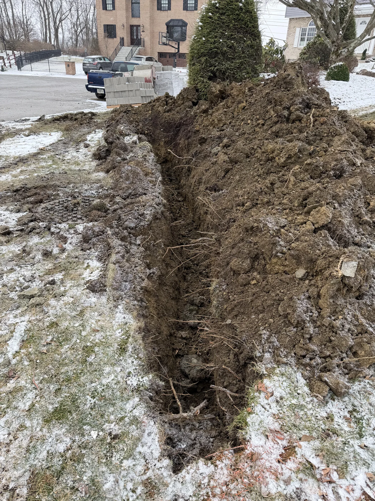 Excavated soil and disturbed sod on a sloped yard during winter excavation work in Pittsburgh